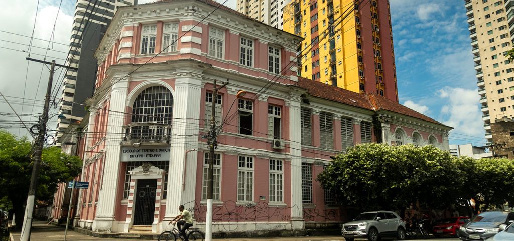 Fotografia da fachada da Escola de Teatro e Dança da UFPA. É um prédio histórico nas cores branca e rosa.