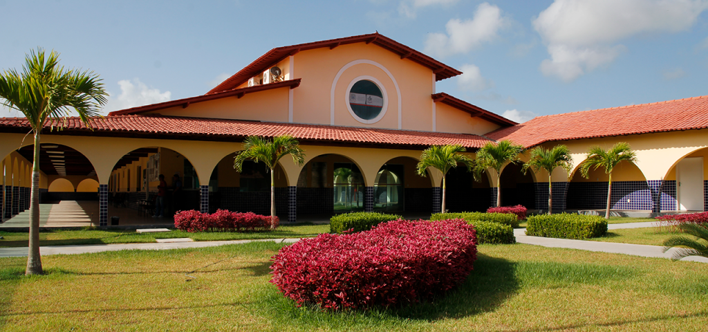 Fotografia interna do Campus Universitário de Salinópolis da UFPA. Aparece o prédio principal atrás de um jardim gramado e florido.