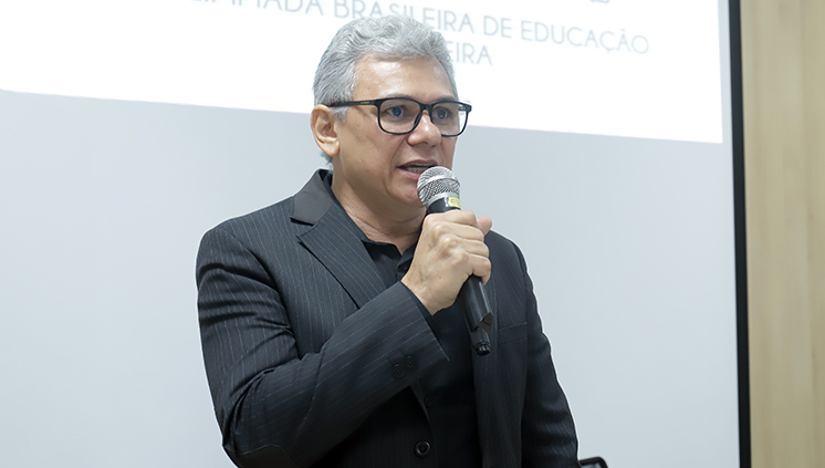 Foto do professor Evaldo Silva, coordenador regional das Olimpíadas. O professor fala ao microfone.