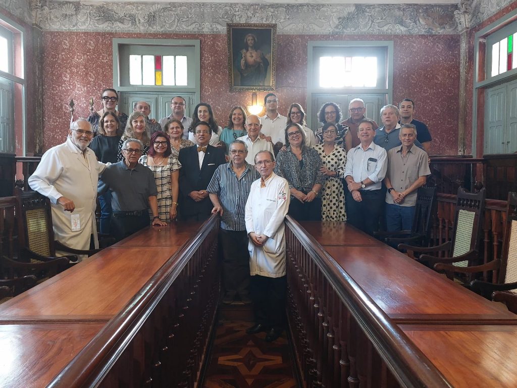Fotografia dos membros fundadores da  Associação dos Ex-Alunos da Faculdade de Medicina do Instituto de Ciências Médicas da UFPA reunidos no Salão Nobre da Faculdade. 