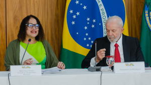 Fotografia da ministra de Ciência e Tecnologia Luciana Santos falando em uma bancada. Ao seu lado, está o presidente Lula.