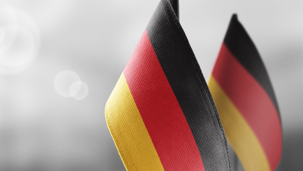 Foto com fundo desfocado. Em destaque, em primeiro plano, pequenas bandeiras da Alemanha.