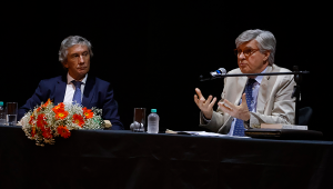 Fotografia do o jurista e ex-ministro da Cultura de Portugal, José António de Melo Pinto Ribeiro, discursando em uma bancada. Ao seu lado, está sentado o embaixador de Portugal no Brasil, Luís Faro Ramos.