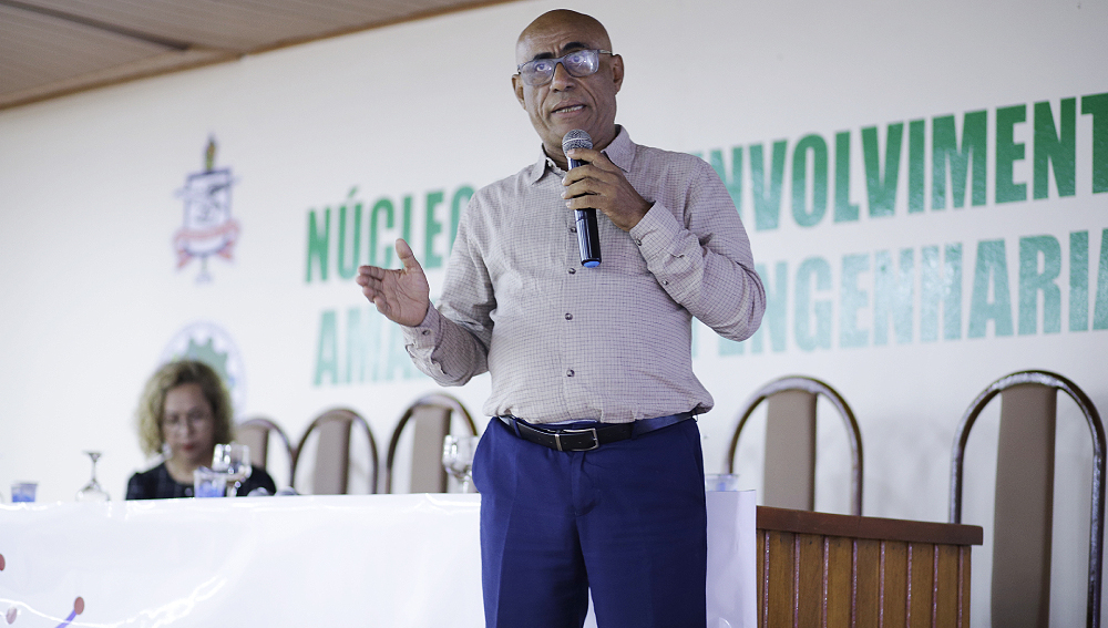 Fotografia do vice-reitor da UFPA, professor Gilmar Pereira da Silva. O professor é um homem negro, usa óculos quadrados de armação preta, veste uma calça azul marinho e um blusa clara. O professor gesticula e fala ao microfone.