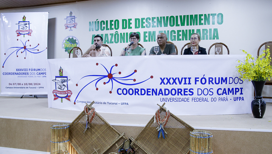 Fotografia registra a mesa de um evento. Na mesa, o vice-reitor da UFPA, Gilmar Pereira é acompanhado por um professor e duas professoras. Na frente da mesa há um banner com a seguinte informação: XXXVIII FÓRUM DOS COORDENADORES DOS CAMPI - UNIVERSIDADE FEDERAL DO PARÁ - UFPA.