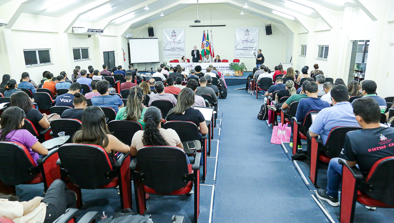 Fotografia plano aberto de um auditório lotado.