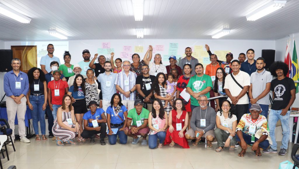 Fotografia registra diversas pessoas posando para a foto. Algumas estão na frente agachadas e outras estão atrás em pé. Na fotografia, ainda é possível ver um pequeno número de pessoas levantando um dos braços com a mão fechada.