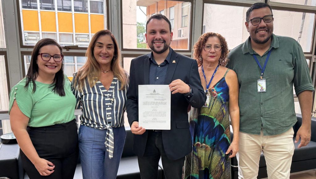 Fotografia posada de representantes da Progep. Entre eles está o pró-reitor, ìcaro Pastana, que segura e mostra para a câmera um documento.