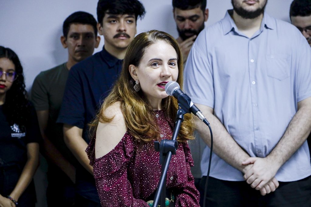 Fotografia da vice-reitora da UFPA, Loiane Prado Verbicaro. Ela é uma mulher branca, de cabelos loiros. Ela fala ao microfone. 