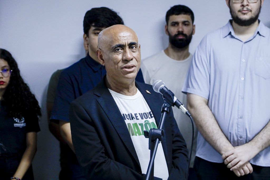 Fotografia do reitor da UFPA, Gilmar Pereira da Silva. Ele é um homem negro e calvo. Usa terno de cor azul marinho e camiseta branca. 