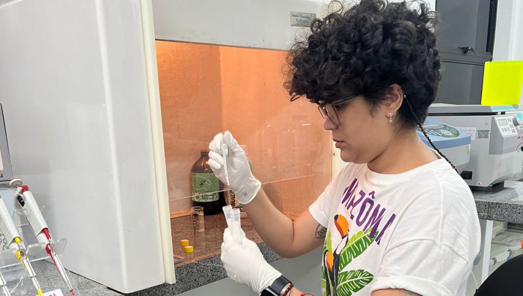 Fotografia registra Viviane Firmino manuseando um tudo de ensaio e um dosador.