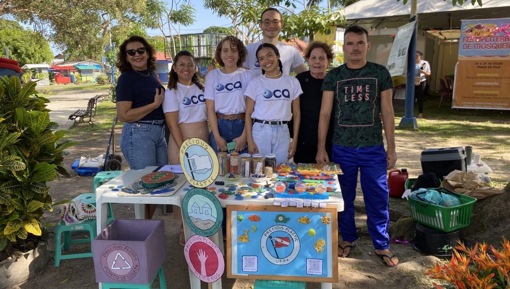 fOTOGRAFIA POSADA DE UM GRUPO DE PESSOAS. aLGUNS VESTEM CAMISAS COM A SIGLA DO oca.