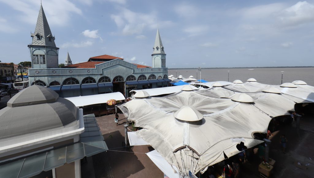 Fotografia mostra uma área do mercado Ver-o-Peso, em Belém. A foto registra tendas brancas e , ao fundo, a lateral do mercado de peixe.