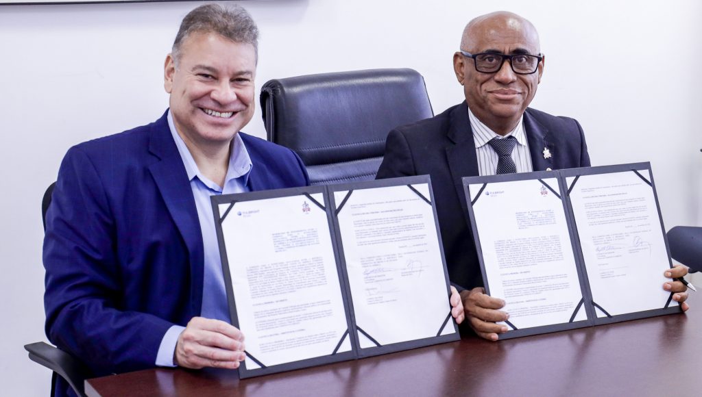 Fotografia posada do reitor da UFPA, acompanhado do encarregado de negócios da da Embaixada dos EUA no Brasil, Gabriel Escobar. Os dois mostram para a câmera uma pasta com duas folhas de papel.