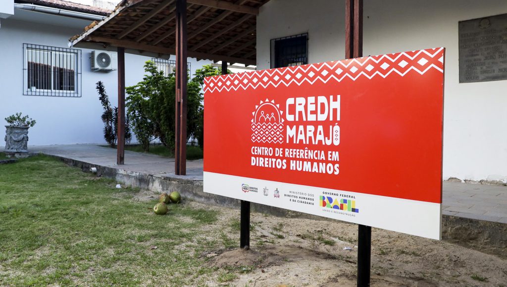 Fotografia registra a placa de identifica do prédio do CENTRO DE REFERÊNCIAS EM DIREITOS HUMANOS - CREDH MARAJO. Abaixo da identificação, a logo do Governo federal, do Ministérios dos Direitos Humanos e da Cidadanioa, e o brasão da UFPA.