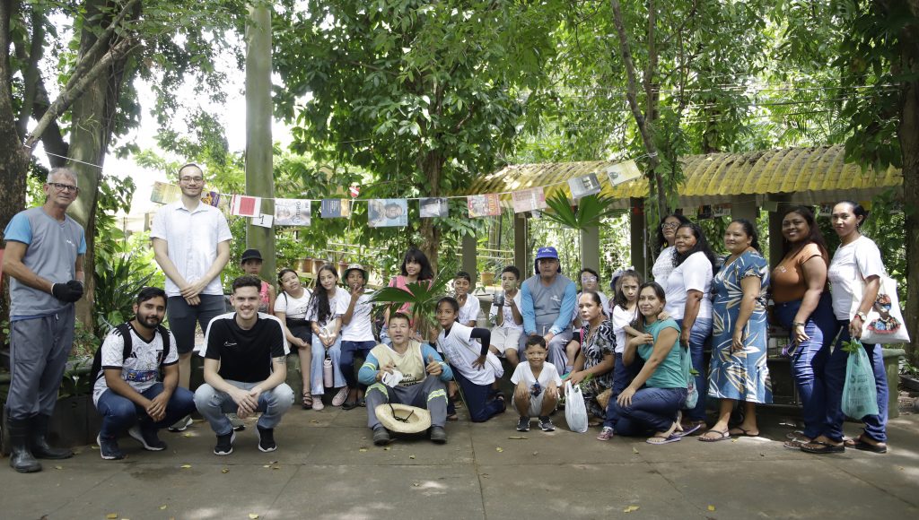 Fotografia posada de um grupo de pessoas em um ambiente aberto com árvores.