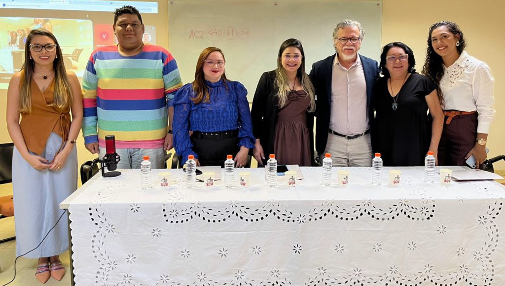 Fotografia posada de um grupo de sete pessoas. Todos olham pra foto e sorriem.