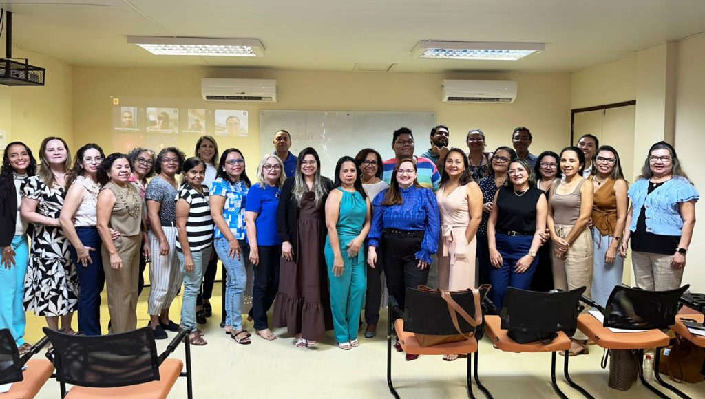 Fotografia posada de um grupo de pessoas. Todos olham pra foto e sorriem.