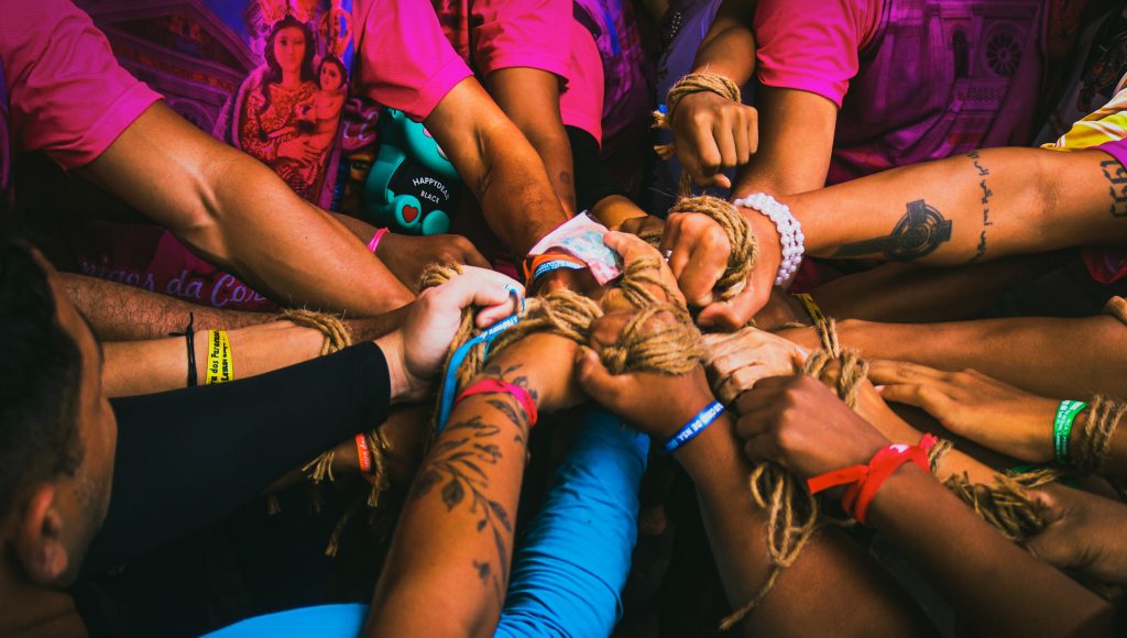 Fotografia de várias mãos segurando pedaços de corda.