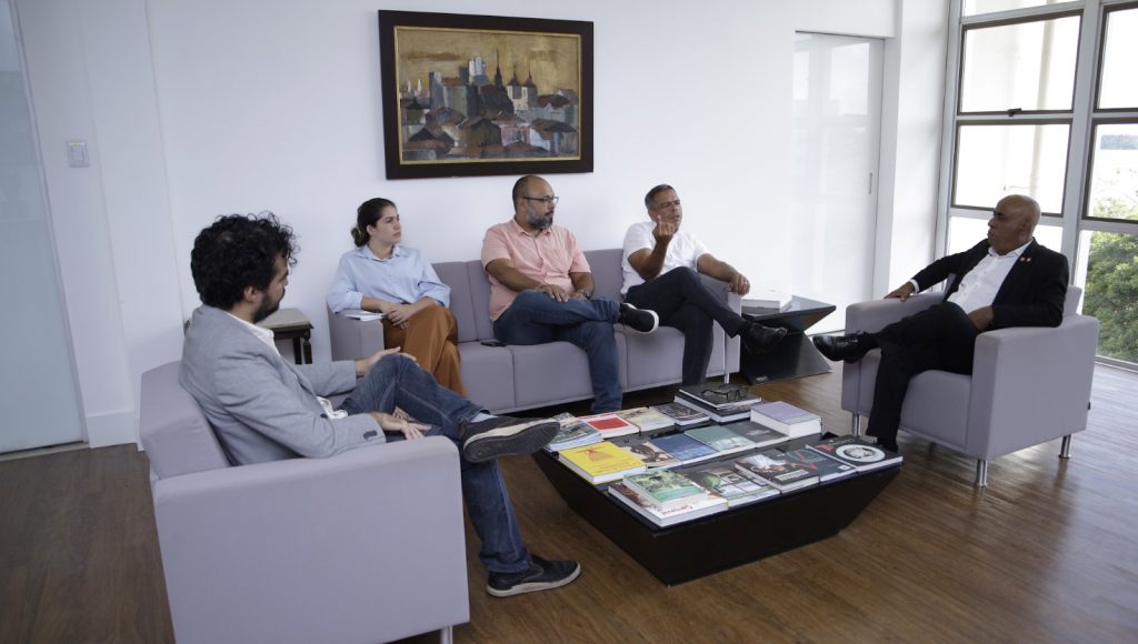 Fotografia de um grupo de pessoas sentada em um semi círculo.