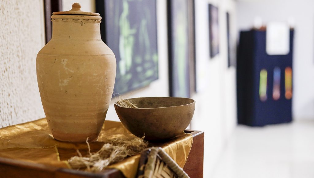 Fotografia registra um jarro de barro e uma cuia que integram a exposição.