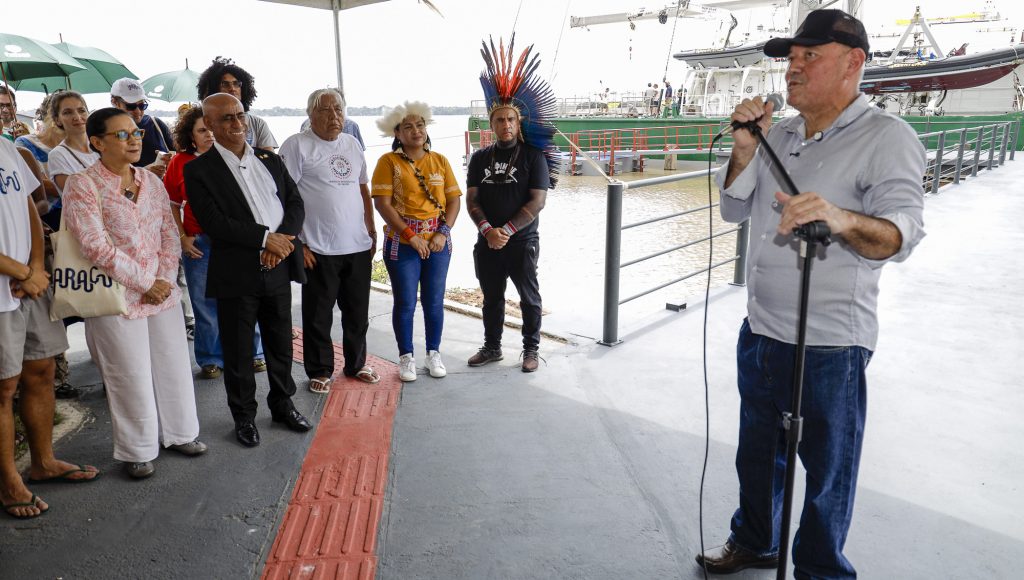 Fotografia registra o momento que o diretor da Fadesp, Roberto Ferraz, fala ao microfone, sendo observado por outras pessoas.