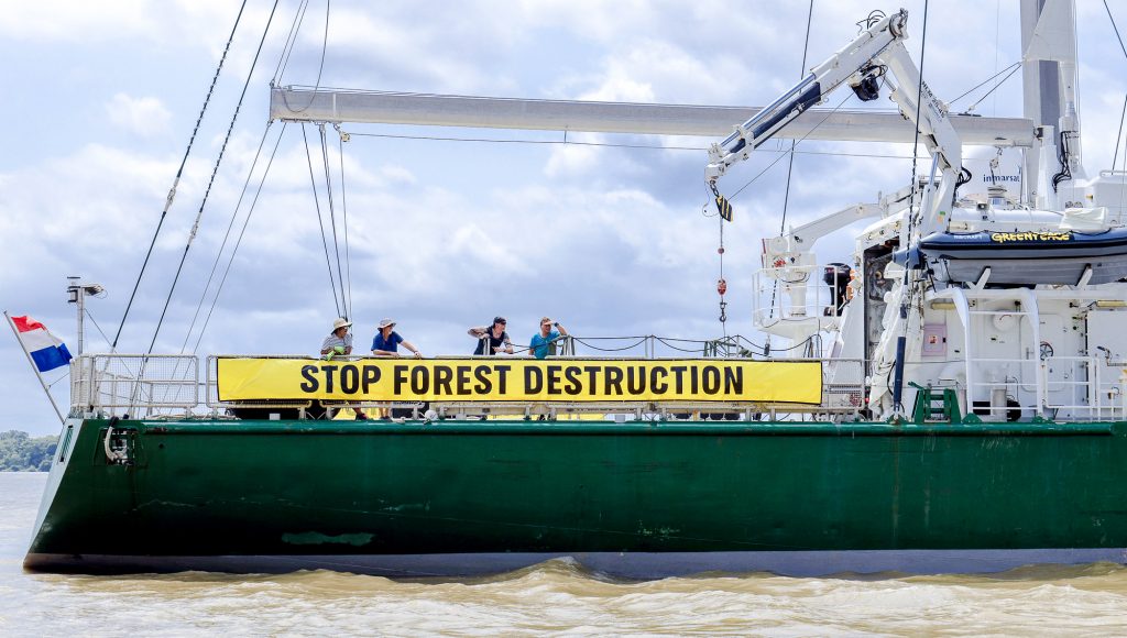 Fotografia de parte de uma embarcação verde. Na lateral da embarcação há uma faixa com o seguinte texto: STOP FOREST DESTRUCTION.