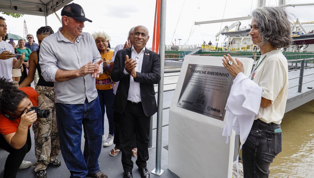Fotografia registra o momento de inaugração da placa do Trapiche Ribeirinho. Ao lado da placa estão o reitor da UFPA, Gilmar Pereira da Silva, o diretor da Fadesp, Roberto Ferraz, e a representante do Greenpeace, Carolina Pasquale.