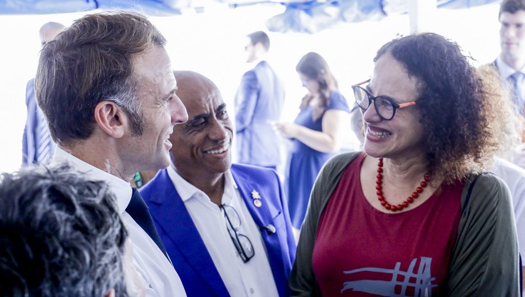 Fotografia registra o encontro do presidente da França, Emmanuel Macron com a ministra de Ciência e Tecnologia, Luciana Santos, e o reitor da UFPA, Gilmar Pereira da Silva. Os três sorriem.