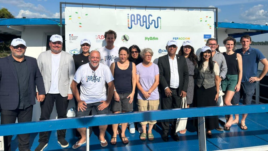 Fotografia posada de uma grupo de pessoas. Todos estão em frente a um banner com o nome IARUÇU. No grupo, está o reitor da UFPA, Gilmar Pereira da Silva.