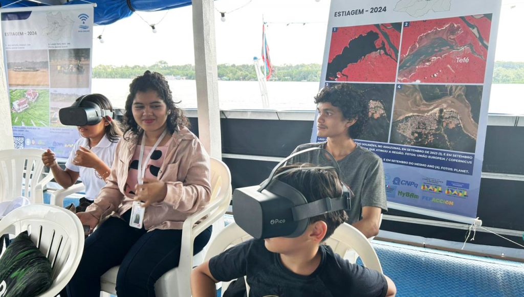 Fotografia registra quatro pessoas, sendo uma mulher adulta e dois jovens. Os jovens estão usando óculos de realidade virtual.