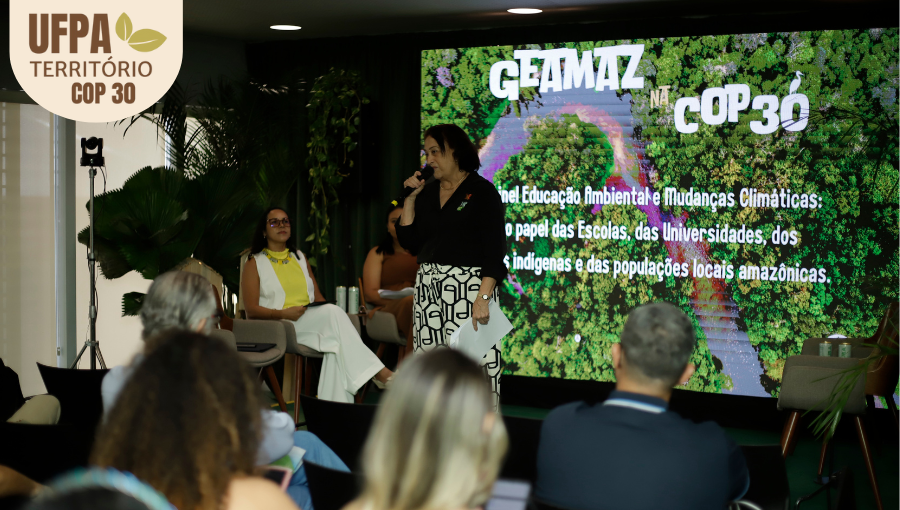 Fotografia registra a professora Ludetana, em cima do palco, falando ao microfone. Atrás dela há um painel com a projeção: GEAMAZ. Sobre a foto, um selo identifica: UFPA TERRITÓRIO DA COP.