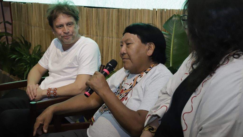 Fotografia registra o indígena Davi Kopenawa falando ao microfone.