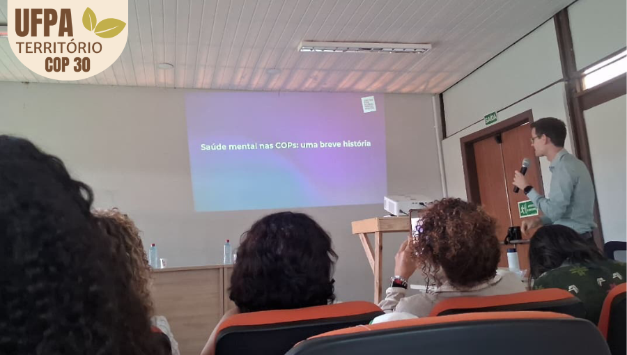 Fotografia registra um professor fazendo uma projeção em um telão. Sobre a foto, um selo identifica: UFPA TERRITÓRIO DA COP.