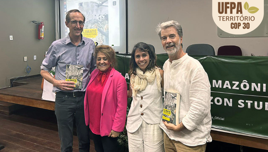 Fotografia posada registra um grupo de quatro pessoas, dois homens e duas mulheres, dentro de um auditório. Sobre a foto, um selo identifica: UFPA TERRITÓRIO DA COP.