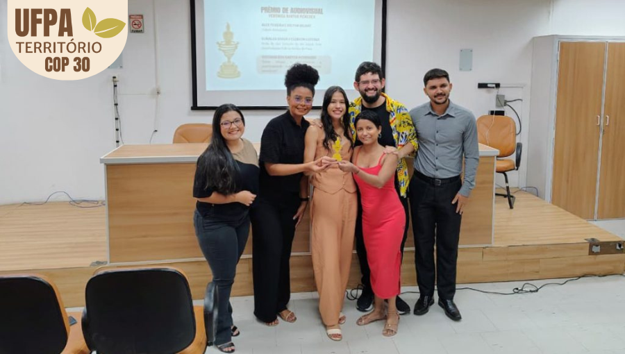 Fotografia registra um grupo de jovens segurando um troféu. Todos sorriem e olham pra foto.