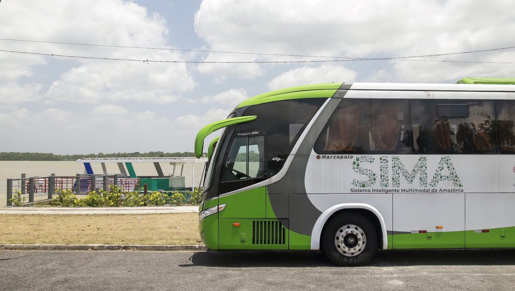 Fotografia registra parte de um ônibus que está parado na orla.