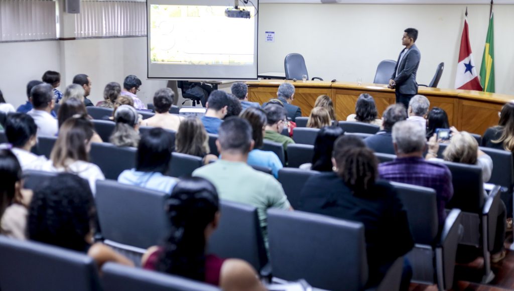 Fotografia registra um auditório lotado, de frente para um telão.
