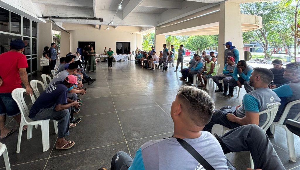 Foto registra um grande grupo de pessoas sentados em cadeiras dispostas em um círculo.