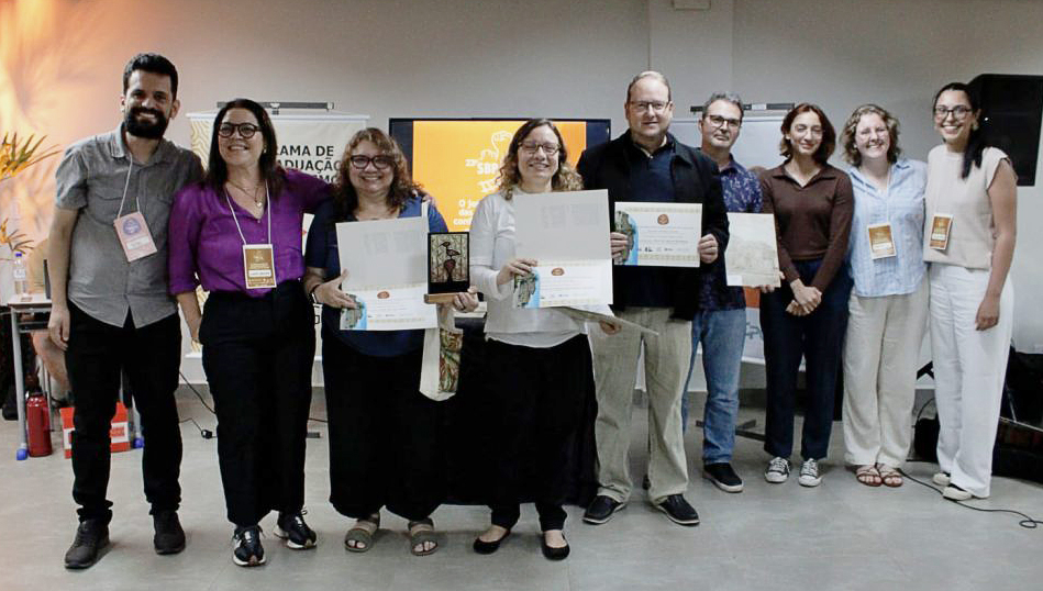 Fotografia posada de um grupo de pessoas. Todos seguram certificados.