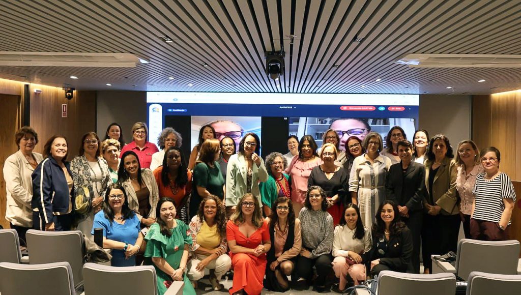 Fotografia posada de um grande grupo de mulheres dentro de um auditório.