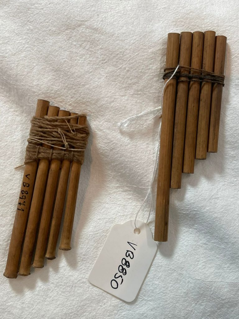 Fotografia de dois instrumento indígenas semelhantes a instumentos de sopro.