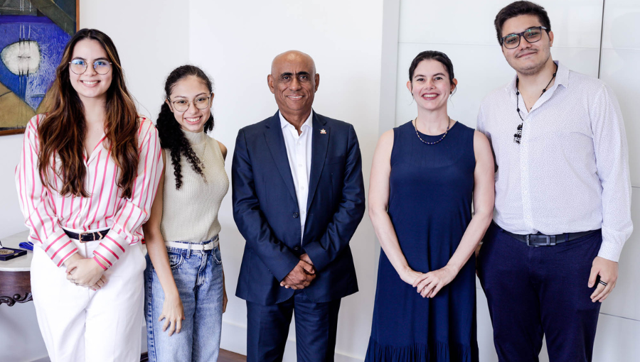 Fotografia do reitor da UFPA, homem negro e calvo, ao lado de quadro jovens.
