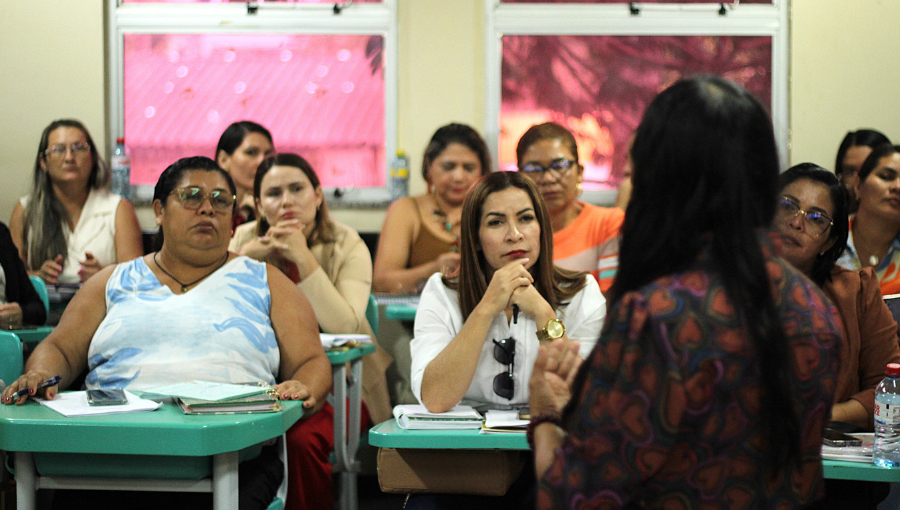 Fotografia registra um grupo de pessoas em uma sala de aula.