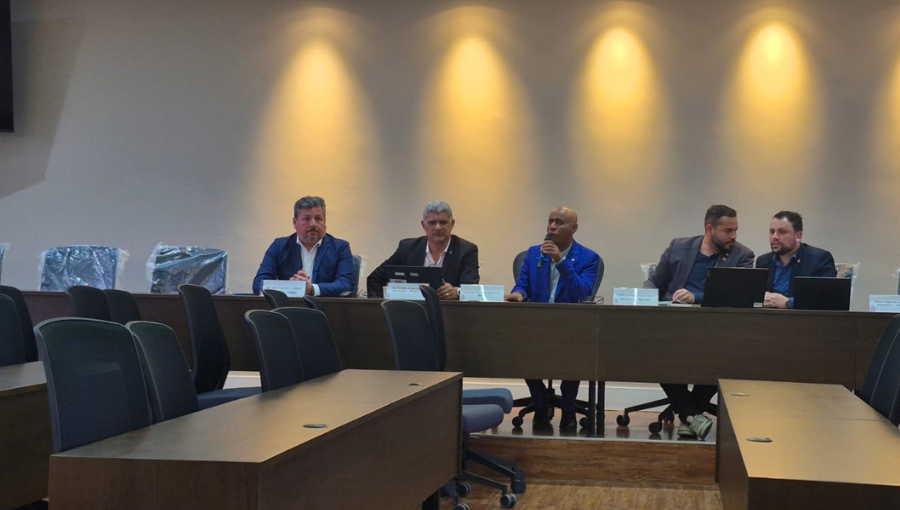 Fotografia mostra cinco homens sentados. Eles estão por detrás de uma mesa. Ao centro, o reitor da UFPA, Gilmar Pereira da Silva, fala ao microfone.