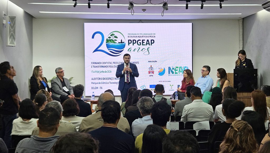 Fotografia registra a plateia de um evento. Ao fundo, em um telão, uma logomarca destaca a mensagem: PPGEAP 20 anos.