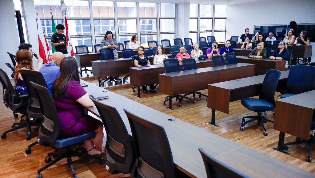 Fotografia registra uma parte da plateia de uma sala de reunião.