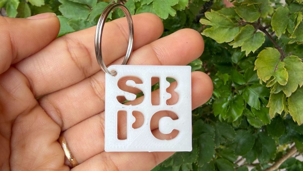 Fotografia registra uma mão segurando um chaveiro com a sigla SBPC.