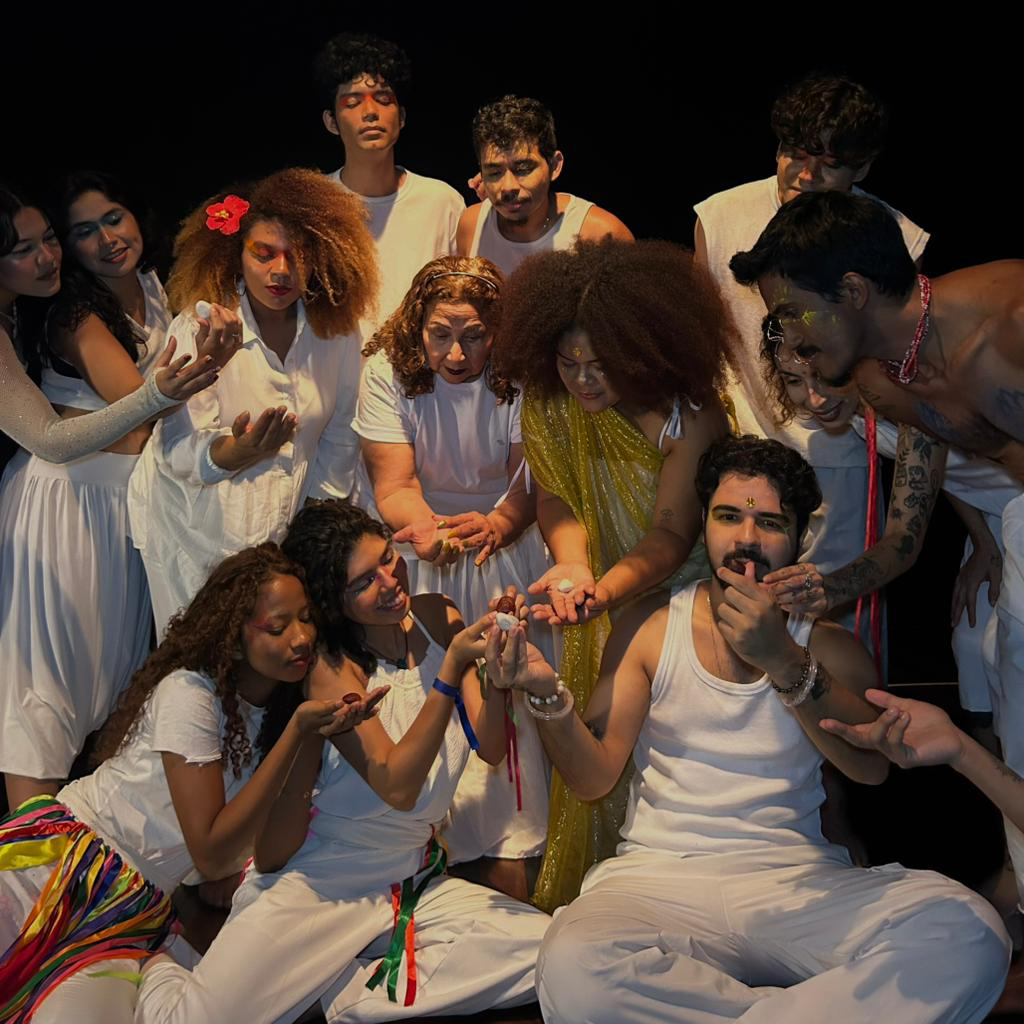 Fotografia registra um grupo de pessoas, todos vestidos de branco, manuseando pedrinhas.