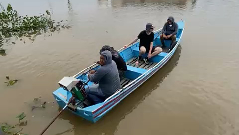 Fotografia registra uma rabeta, pequeno veículo de navegação, com quatro pessoa a bordo. Uma das pessoas manuseia o motor.